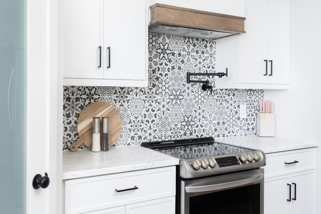 Modern style kitchen with a patterned backsplash and white cabinetry.